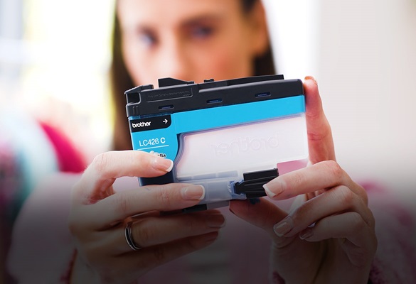 Woman in a pink top with outstretched hands holding a Brother cyan ink cartridge