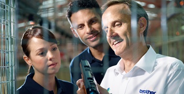 Two men and a woman inspecting a toner cartridges surrounded by a cage