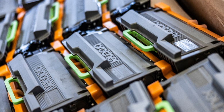 Two men and a woman looking at a toner cartridge